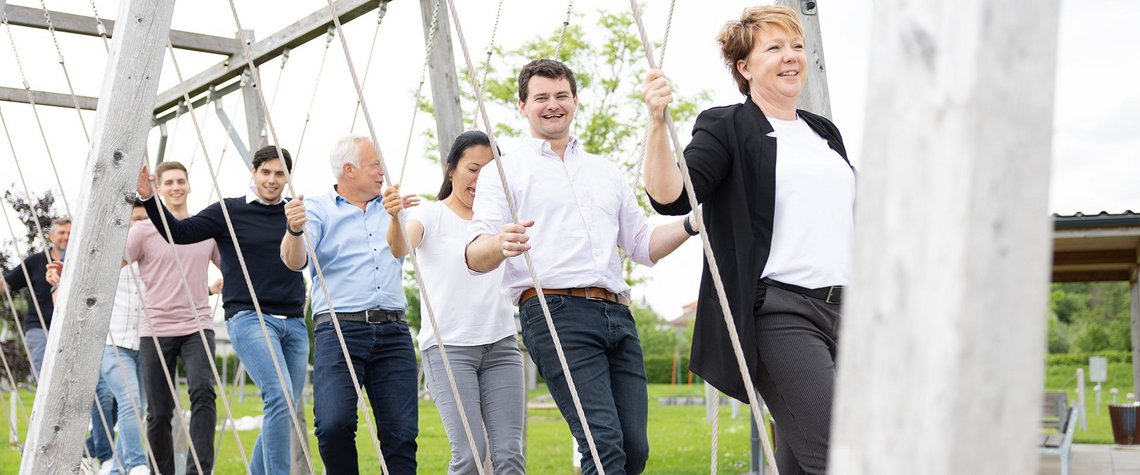 [Translate to Italy:] Smiling people on a rope swing