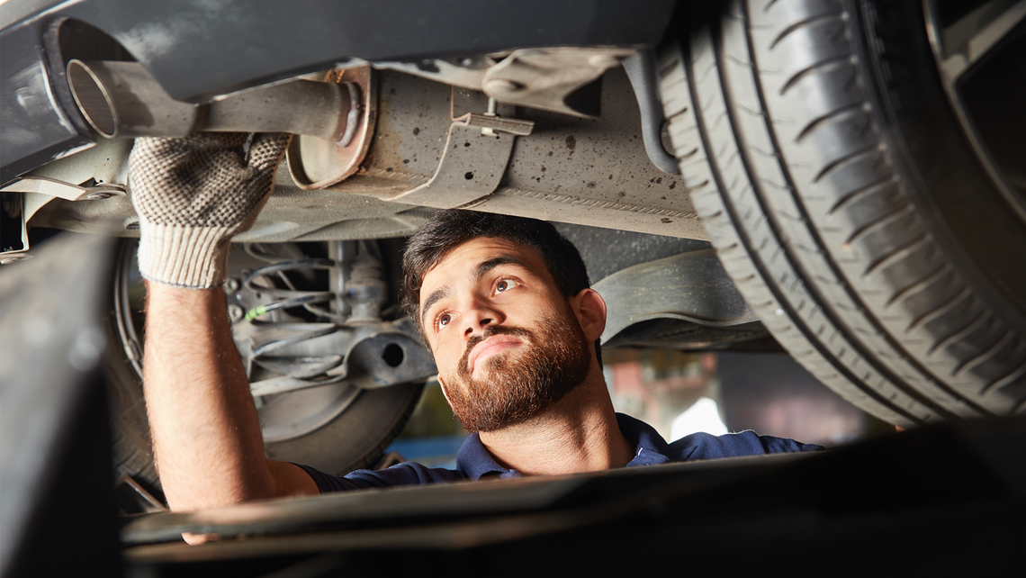 Mechanic working on the underbody of a car